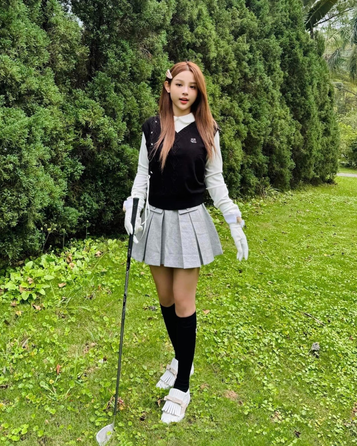 Khi đi chơi golf, Huyền Baby chọn những trang phục thời thượng. Cô chọn áo cổ Peter Pan với gile len, kết hợp cùng chân váy ngắn xếp ly và tất cao đến gối. Tổng thể trang phục thường mang đến cảm giác năng động, trẻ trung nhưng vẫn rất thời trang.