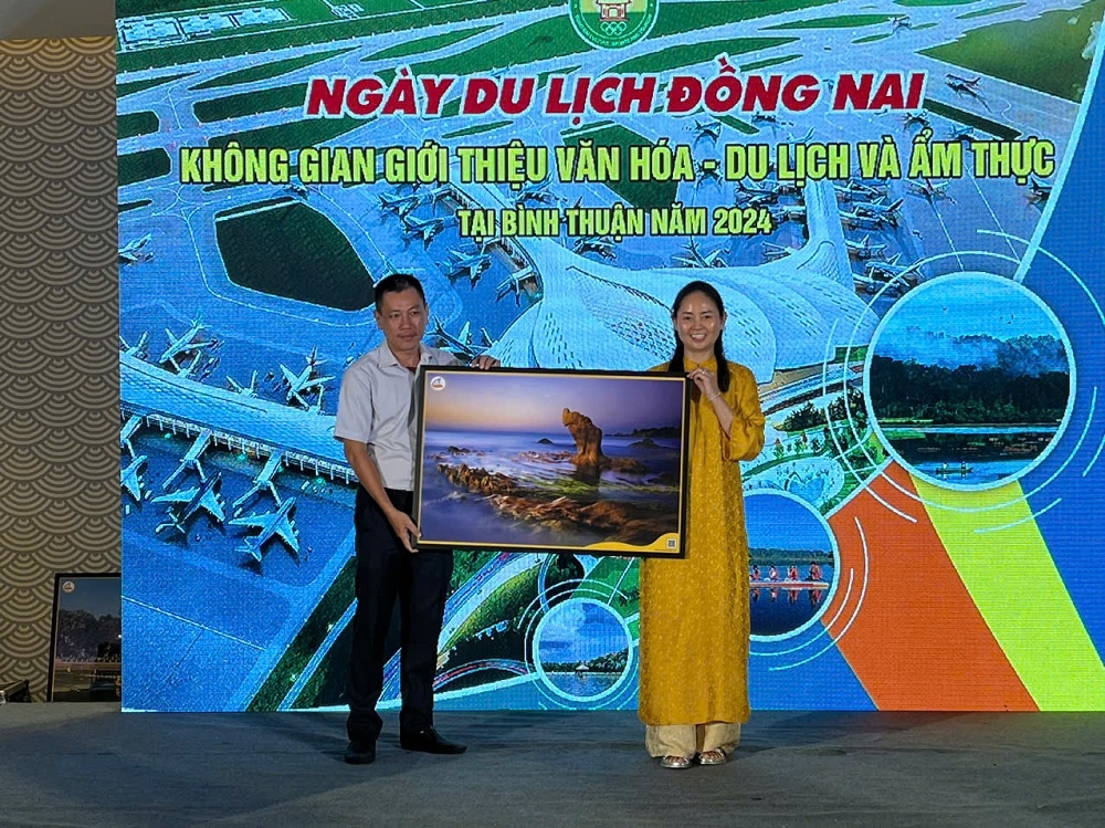 Đại diện ngành du lịch Đồng Nai (nữ) nhận bức tranh lưu niệm từ ngành du lịch Bình Thuận. Ảnh: Nguyên Vũ  