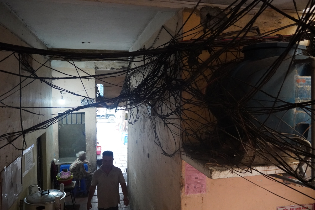 Mặc dù trời nắng to nhưng lối vào chung cư vẫn mờ tối với những bó dây điện chằng chịt Ảnh: Hoàng Minh)