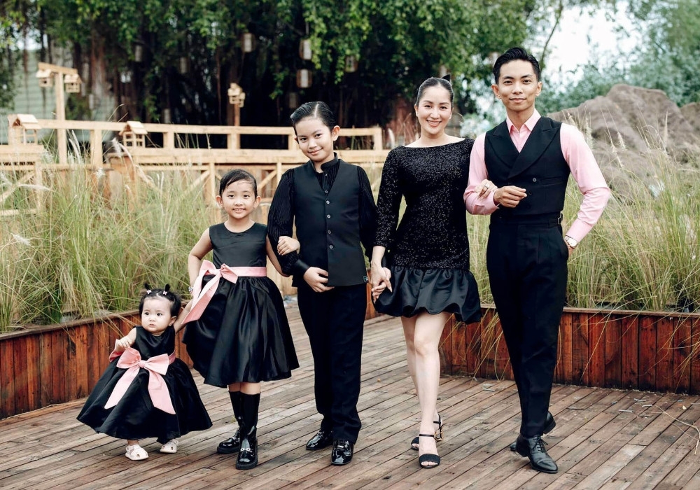 Gia đình Khánh Thi - Phan Hiển tạo dáng với trang phục đen, xếp đội hình theo thứ tự chiều cao tăng dần.