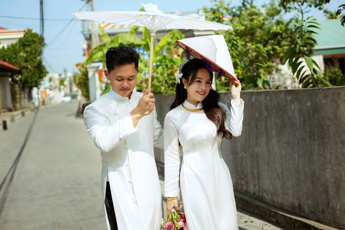 Cô dâu Thái Trinh diện áo dài trắng sánh đôi chú rể Thái Minh trong hôn lễ tổ chức sáng 20/11. Chồng Thái Trinh tên Nguyễn Thái Minh, sinh năm 1999, làm việc trong ngành nhựa, vẻ ngoài được bạn bè khen ưa nhìn, chiều cao nổi bật.