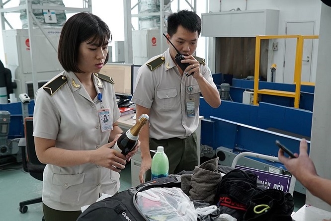 Nhân viên an ninh hàng không kiểm tra giấy tờ của hành khách trước khi vào khu vực soi chiếu an ninh để lên máy bay.