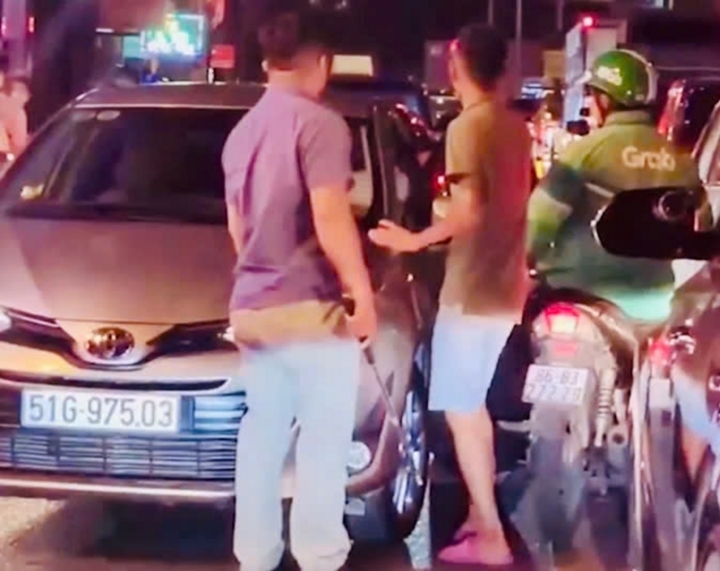 Người đàn ông cầm gậy đánh tài xế xe công nghệ giữa đường đông đúc. (Ảnh cắt từ clip)