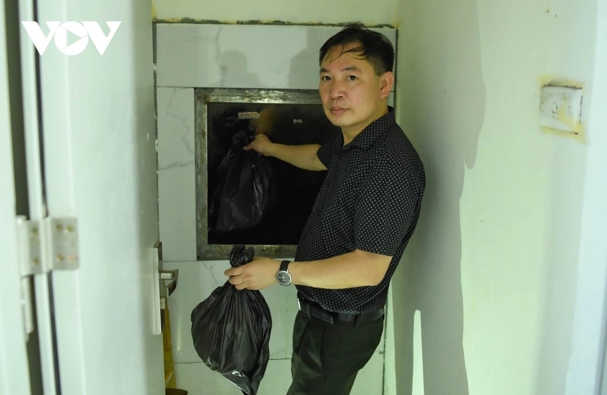 Ông Nguyễn Bá Huấn đưa rác phân loại vào ống rác chung cư
