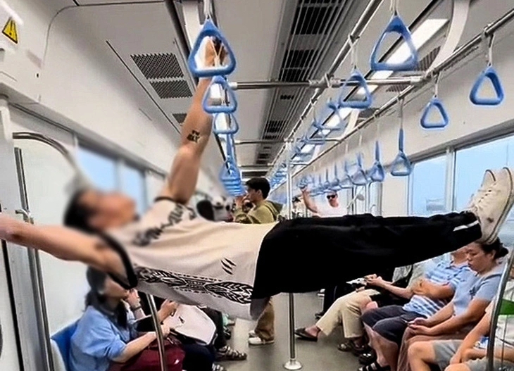Hình ảnh nam thanh niên dùng tay nắm, thanh sắt dọc trần tàu điện metro để hít xà đơn. (Ảnh cắt từ video)