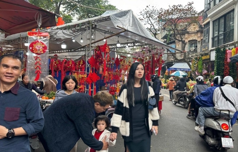 Visitors at the market seek peach flowers, kumquat trees, and ornamental plants for decoration, while also enjoying the Tet atmosphere.