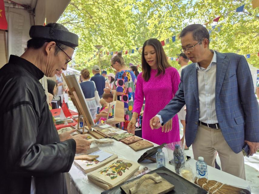 Đại sứ Phạm Hùng Tâm và phu nhân thích thú trước bức tranh Đông Hồ được trưng bày tại Quầy Việt Nam. Nguồn: ĐSQ Việt Nam tại Australia