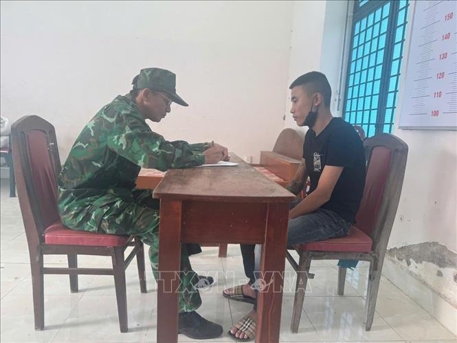 Cán bộ nghiệp vụ thuộc Đồn Biên phòng Cửa khẩu quốc tế Mộc Bài làm việc với đối tượng Phạm Minh Hải. (Ảnh: TTXVN)