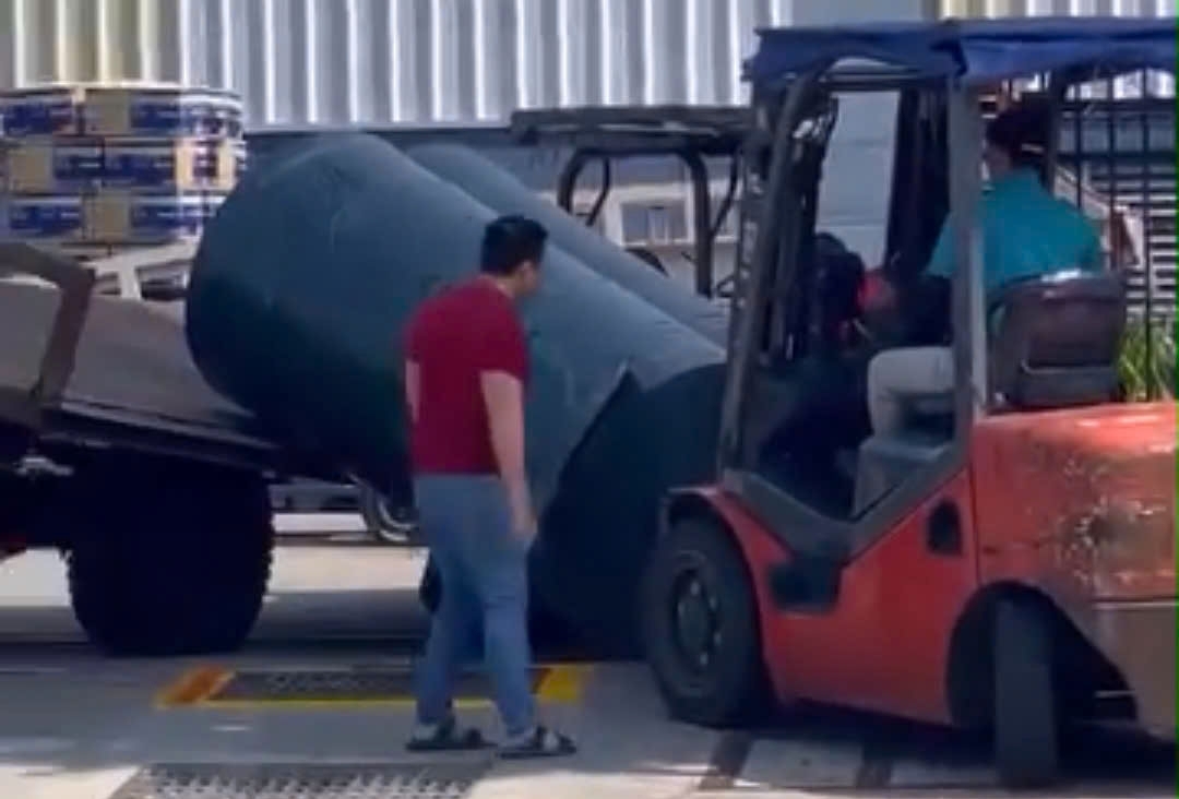 Mọi người cố gắng kéo 3 cuộn vải ra bên ngoài để cứu nam bảo vệ (ảnh cắt từ video)