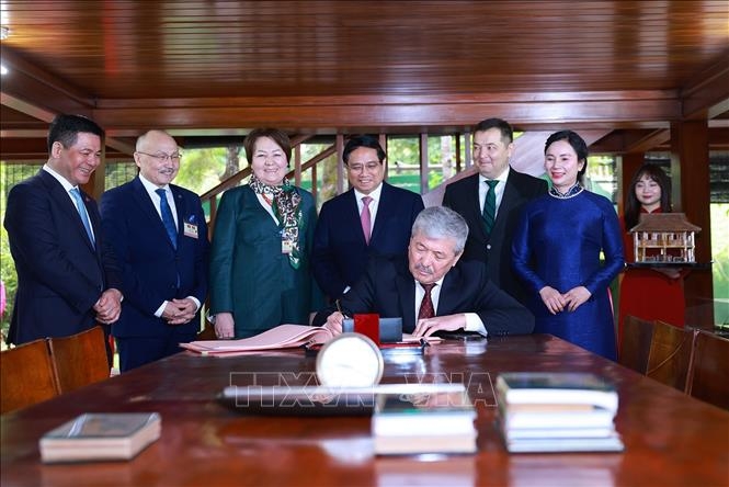 Thủ tướng Kyrgyzstan Adylbek Kasimalyev viết lưu bút khi đến thăm Di tích Bác Hồ. (Ảnh: Dương Giang/TTXVN)