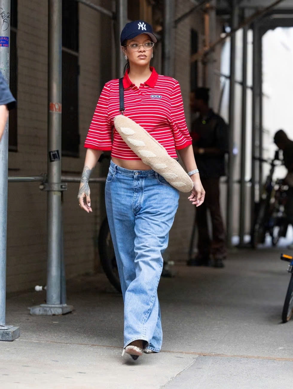 Ngày 8/5/2025, Rihanna được bắt gặp trên đường phố New York trong trang phục đậm chất thoải mái nhưng không kém phần sành điệu. Cô diện áo polo kẻ sọc của Martine Rose phối cùng quần jeans cạp cao từ Bottega Veneta, tạo nên tổng thể năng động nhưng vẫn giữ nét cá tính. Nữ ca sĩ hoàn thiện outfit với túi đeo chéo Fendi baguette, mũ bóng chày New York Yankees và đôi giày cao gót Amina Muaddi họa tiết da rắn.