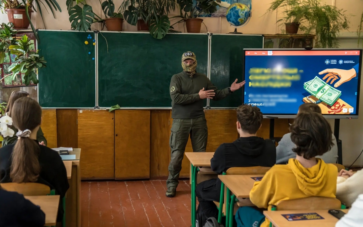 Nhân viên Cơ quan An ninh Ukraine (người mặc đồ che kín mặt) hướng dẫn học sinh Ukraine tại tỉnh Lviv cách ứng phó với các màn tiếp cận và tuyển dụng của tình báo Nga. Ảnh: Nytimes.