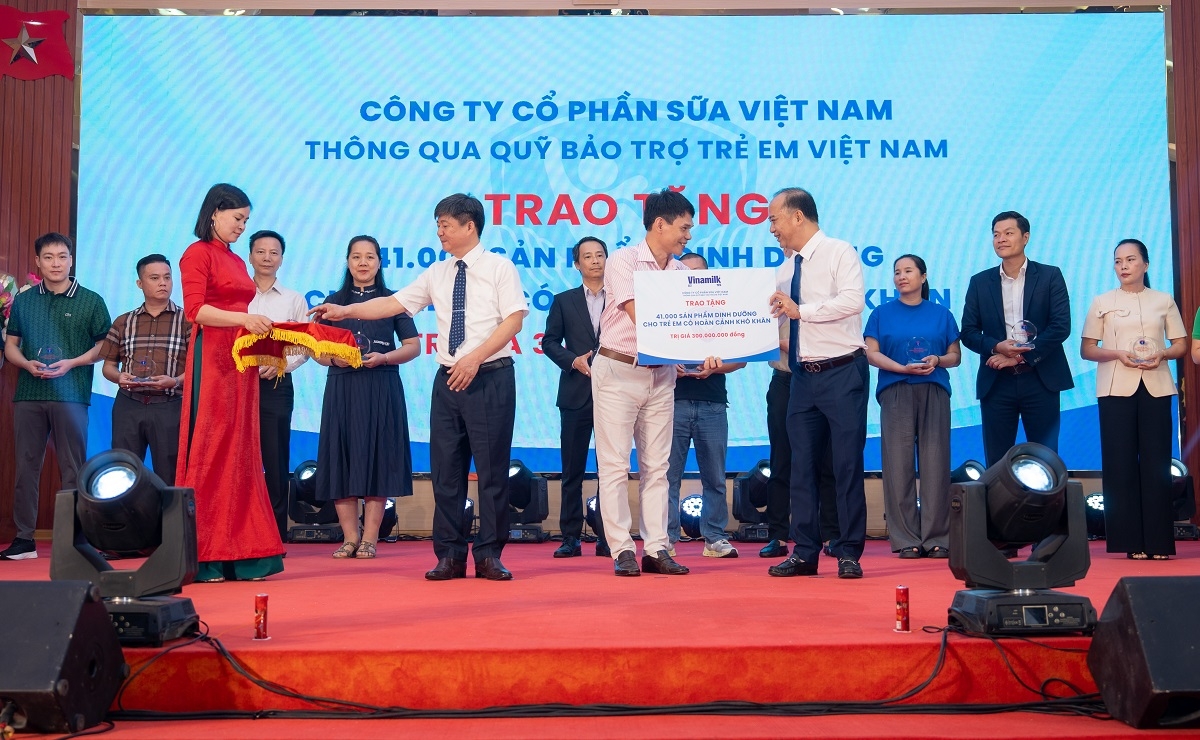 Ông Phạm Tuyên, Giám đốc chi nhánh Vinamilk Hà Nội (đứng giữa) trao bảng tượng trưng món quà 41.000 hộp sữa cho trẻ em Phú Thọ