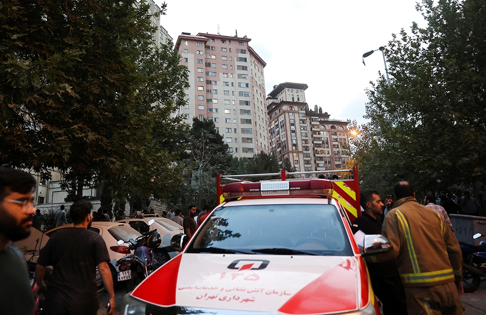 Mọi người tụ tập trên đường phố gần một xe cứu thương sau cuộc không kích của Israel vào Tehran, Iran ngày 13/6. Ảnh: Reuters