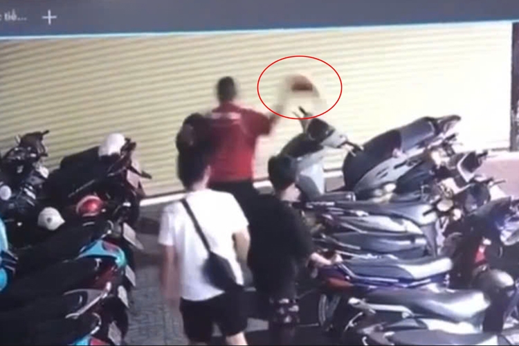 Người đàn ông mặc áo đỏ dùng nón bảo hiểm đánh liên tiếp vào đầu thiếu niên. Ảnh cắt từ clip