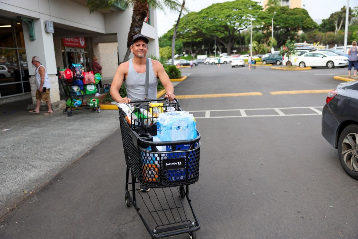 Anh Adam Jung - một người dân ở Honolulu đẩy nước và các nhu yếu phẩm khỏi cửa hàng sau khi các nhà chức trách cảnh báo về nguy cơ sóng thần. Ảnh: Reuters