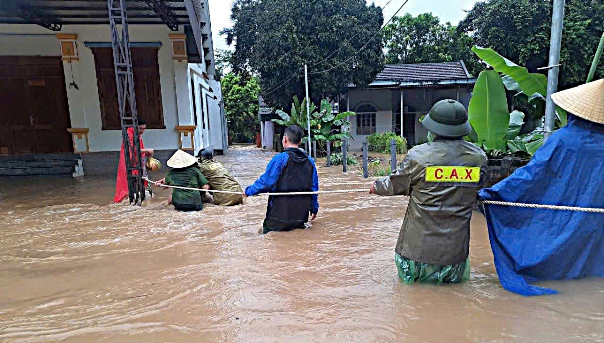 Lực lượng chức năng xã Tiền Phong dùng dây thừng sơ tán người dân khỏi vùng nguy hiểm. Ảnh: KT.