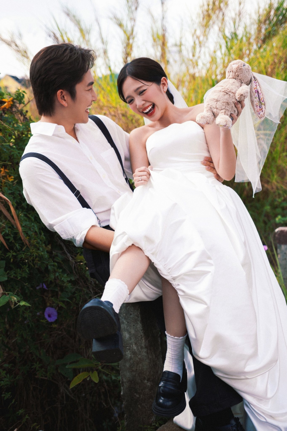 Cô dâu Ngọc Huyền diện váy trắng tinh khôi, cười rạng rỡ, trong khi chú rể Đình Tú lịch lãm với áo sơ mi trắng và quần yếm.