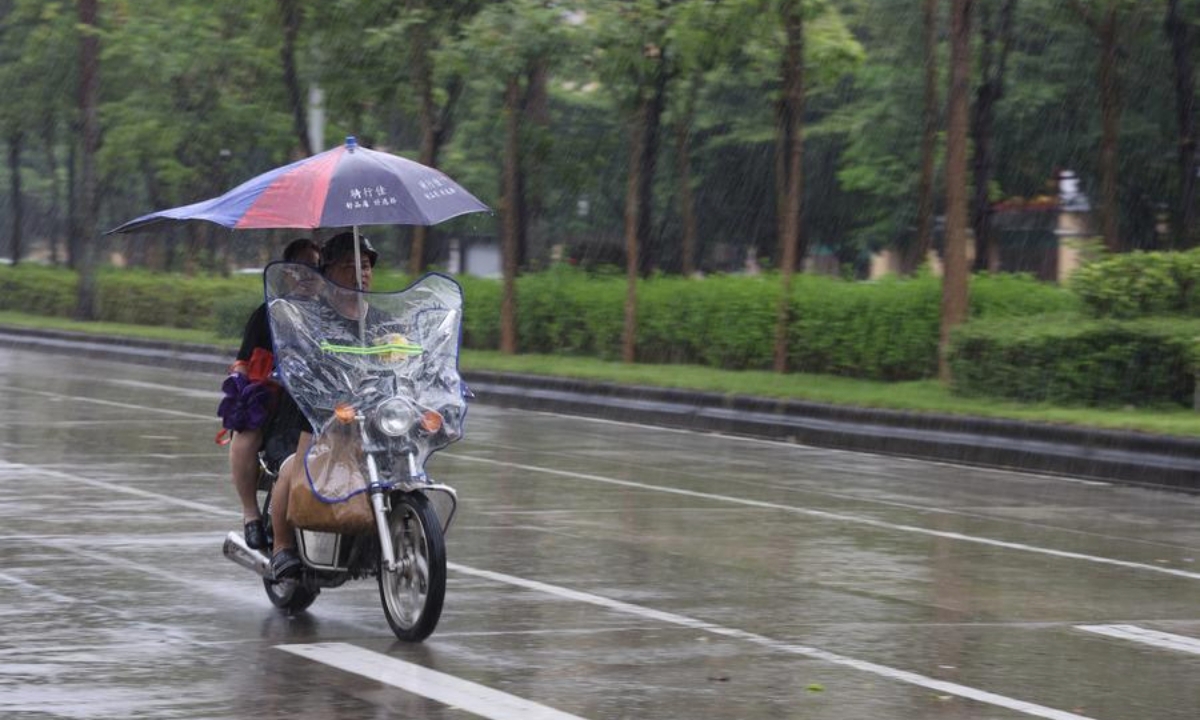 Người dân di chuyển giữa trời mưa ở thành phố Dương Giang, tỉnh Quảng Đông, miền Nam Trung Quốc ngày 8/9, khi Tapah - cơn bão thứ 16 ở nước này trong năm nay - đổ bộ vào tỉnh, buộc trường học phải đóng cửa và hàng chục nghìn cư dân phải sơ tán. Ảnh: Tân Hoa xã