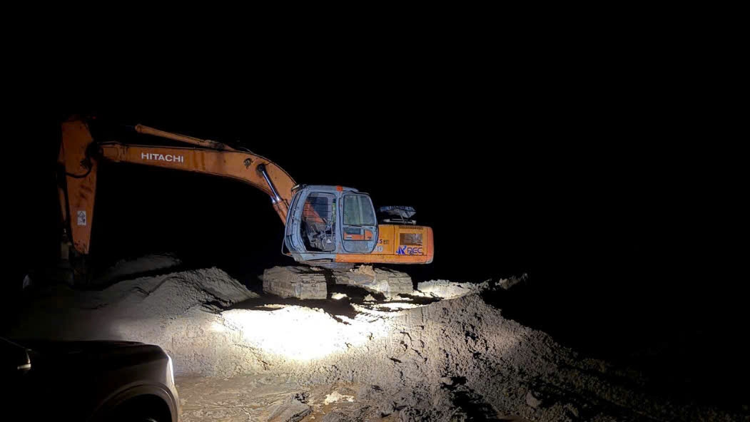 Xe máy đào đang hoạt động trên bãi cát. 