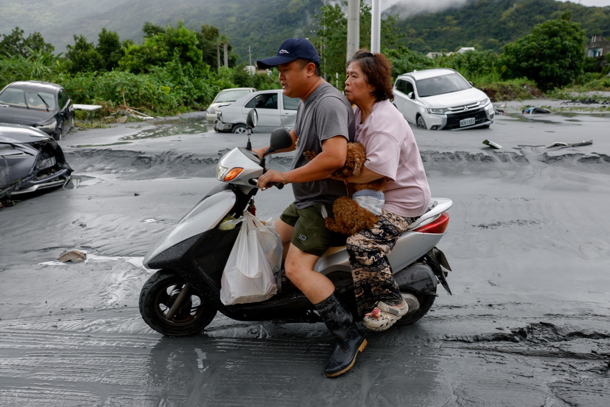 Hong Kong đã ghi nhận 8 người bị thương, những vùng trũng thấp ở Macau có nguy cơ ngập sâu tới 2,5 mét. Trong ảnh, người dân chở đồ đạc và một chú chó cưng sau trận lũ lụt do siêu bão Ragasa gây ra ở Hoa Liên, Đài Loan (Trung Quốc).