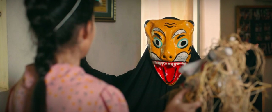 Hoàng đeo mặt nạ con hổ rùng rợn, khoác áo choàng và xuất hiện từ phía sau Quyên