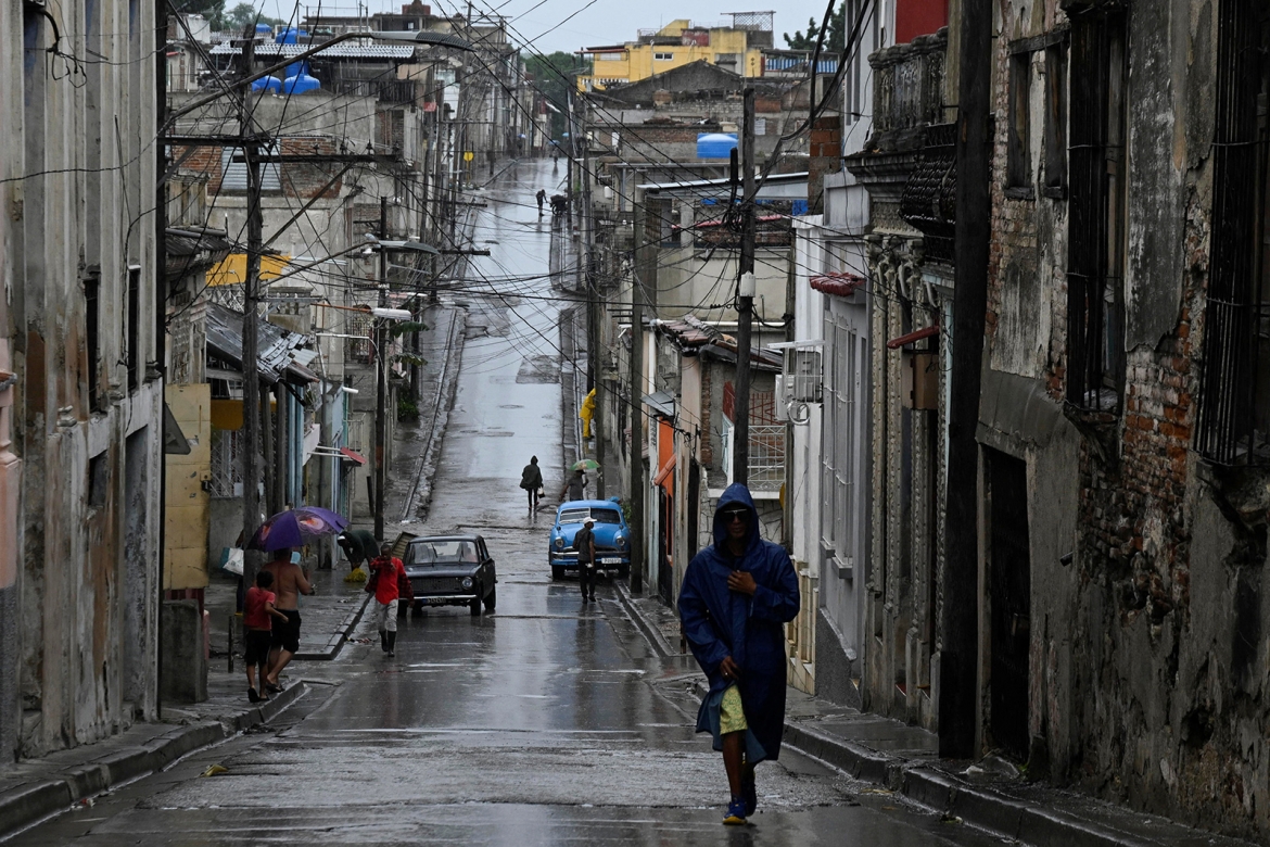 Sau khi quét qua Cuba, siêu bão Melissa dự kiến đổ bộ vào Bahamas. Các nước khác ở Caribbean gồm Haiti và Cộng hòa Dominica cũng sẽ chịu ảnh hưởng do bão, với nguy cơ mưa lớn kéo dài và sạt lở đất. Trong ảnh, người dân đi bộ dọc theo một con phố dưới trời mưa trước khi cơn bão Melissa đổ bộ vào Santiago de Cuba, Cuba, ngày 28/10. Nguồn ảnh: Reuters.