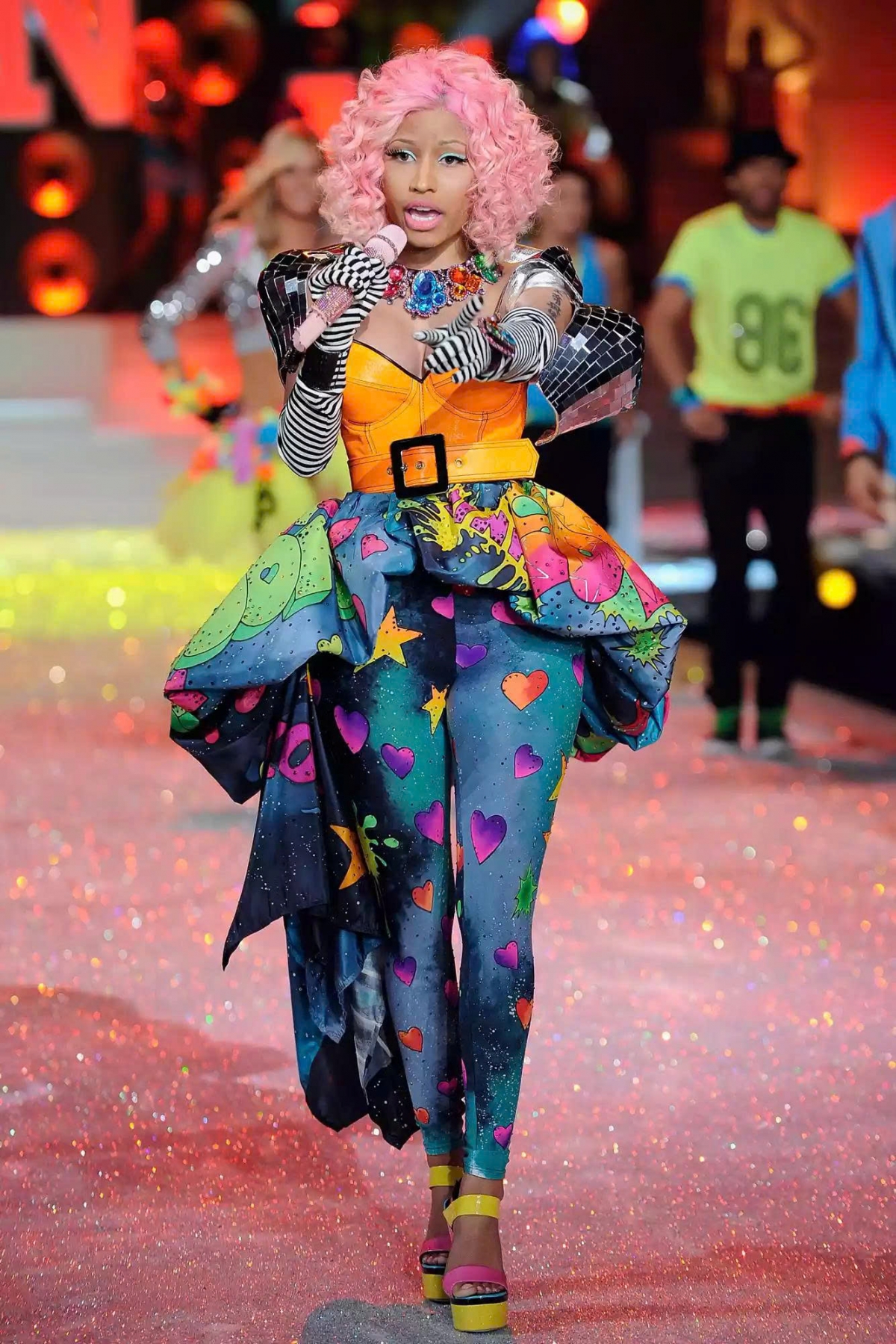 Năm 2011, Nicki Minaj biến sàn diễn Victoria’s Secret thành “vũ trụ sắc màu” của riêng mình. Diện bộ trang phục neon nổi bật, cô trình diễn bản hit “Super Bass” sôi động trong phần PINK, khuấy động cả khán phòng bằng năng lượng và cá tính đặc trưng, đúng kiểu “It’s Nicki’s world, we just live in it!”.