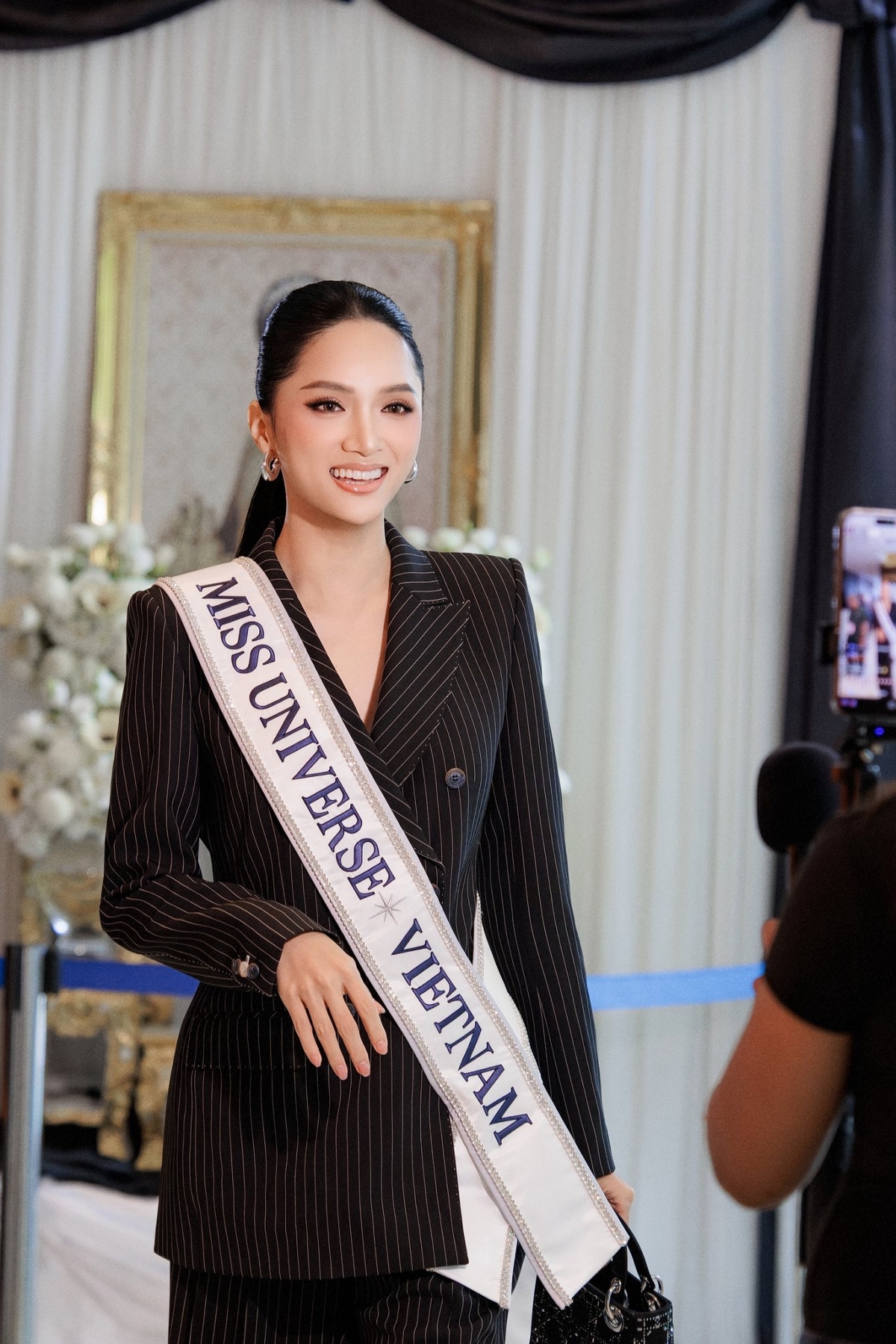 Trong ngày hoạt động thứ 2 của Miss Universe 2025, khi ghi hình phỏng vấn ngắn các thí sinh, Hương Giang lựa chọn bộ vest đen mang đậm vẻ quyền lực. Ở những ngày đầu tham gia đấu trường nhan sắc, nàng hậu thường ưu tiên lựa chọn trang phục mang gam màu trơn cơ bản như trắng, đen hoặc các tông màu trầm.