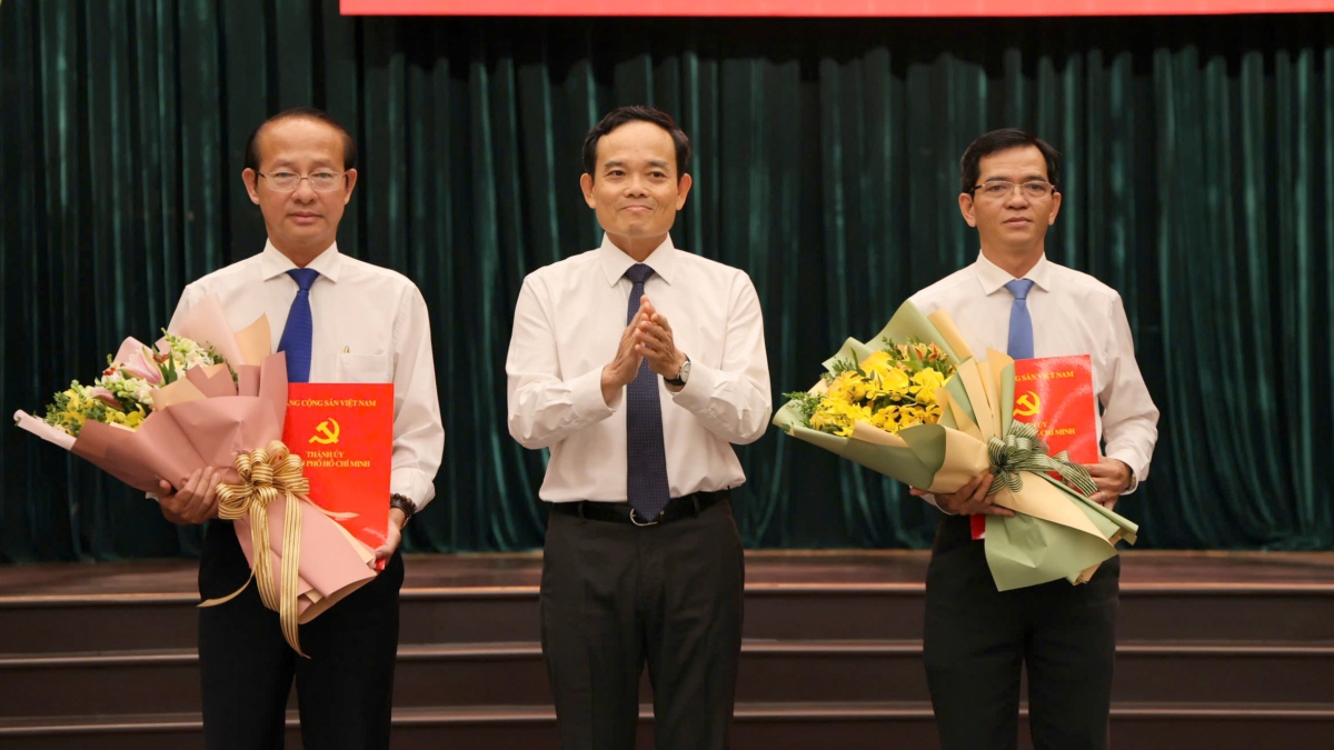 Bí thư Thành uỷ TP.HCM Trần Lưu Quang trao quyết định và chúc mừng ông Võ Văn Dũng (trái) và Dương Trọng Hiếu (phải). Ảnh: L.T