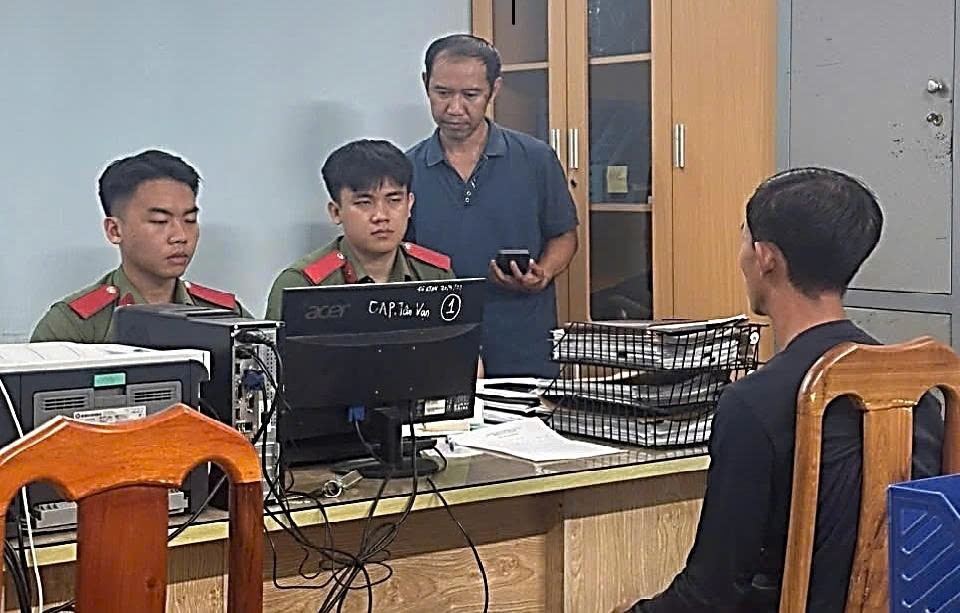 Ông Q.V.T (áo đen, bên phải) tại cơ quan Công an