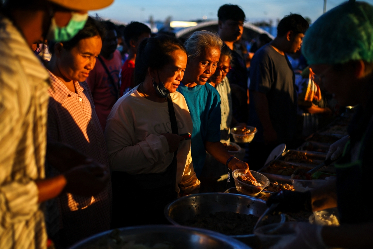 Những người dân phải rời bỏ nhà cửa đứng xếp hàng nhận thức ăn tại một khu vực trú ẩn tạm thời ở tỉnh Buriram, Thái Lan ngày 16/12 giữa bối cảnh giao tranh giữa Thái Lan và Campuchia vẫn tiếp diễn. Ảnh: Reuters