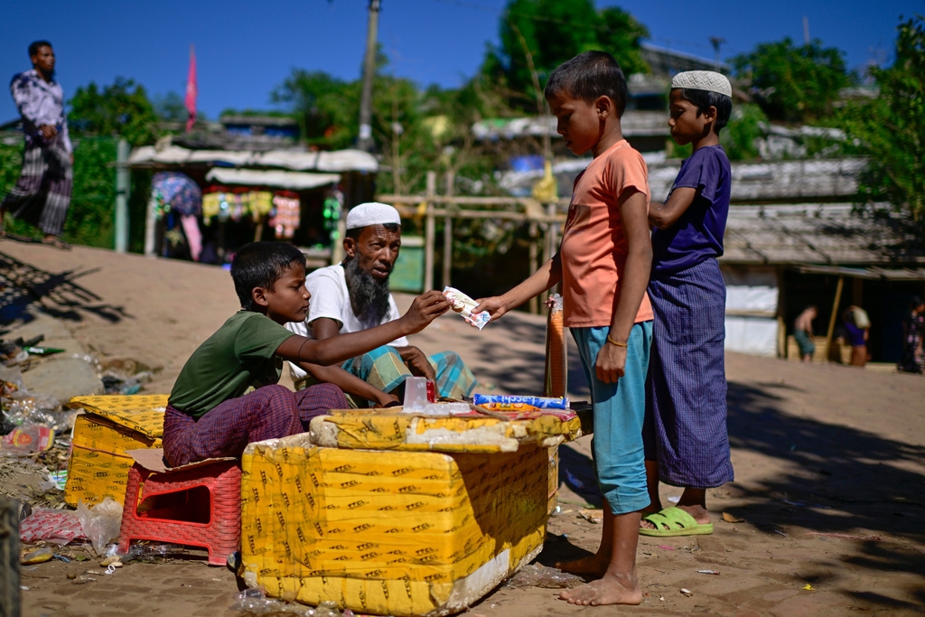 Cậu bé Mohammed Arfan 10 tuổi (bên trái) phải đi bán đồ ăn vặt bên trong trại tị nạn dành cho người Rohingya ở Cox's Bazar, Bangladesh để mưu sinh.