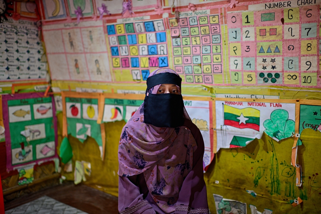 Cô giáo Noor Zia, một người tị nạn Rohingya, trò chuyện với phóng viên khi đang ngồi trong lớp học bên cạnh bức tranh vẽ quốc kỳ Myanmar tại trại tị nạn của người Rohingya ở Cox's Bazar, Bangladesh