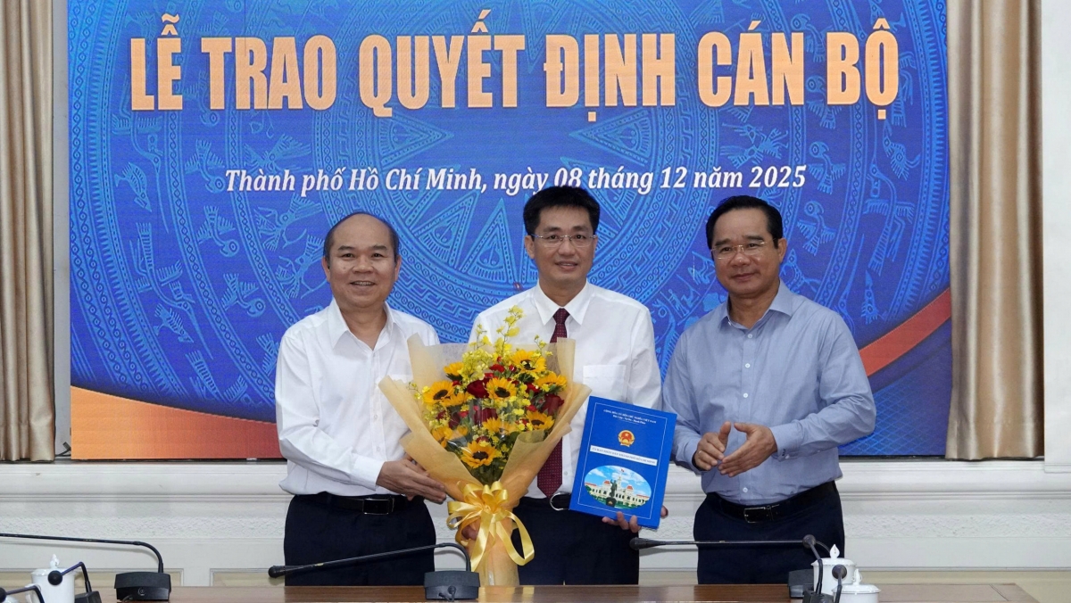 Chủ tịch UBND TP.HCM Nguyễn Văn Được (phải) và Phó Chủ tịch UBND TP.HCM Trần Văn Bảy trao quyết định, trao hoa chúc mừng ông Phạm Văn Nghì. (Ảnh: N.V)