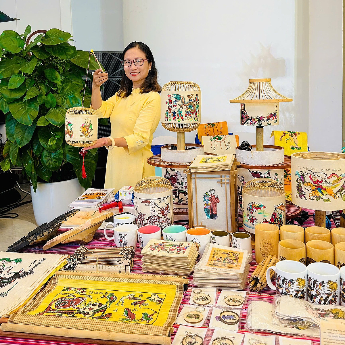 Chị Nguyễn Thị Hữu bên những sản phẩm sáng tạo sử dụng chất liệu tranh dân gian của các bạn trẻ MOC. (Ảnh: NVCC)