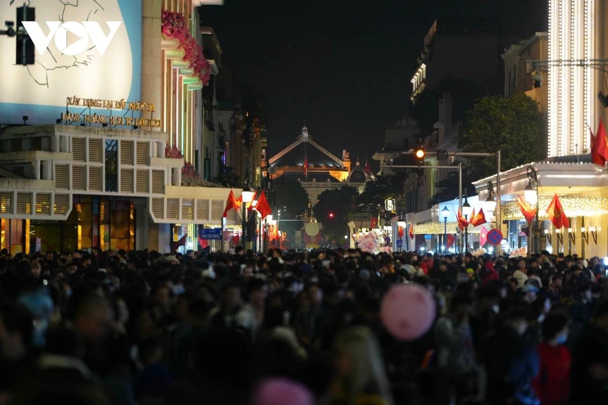 As night falls in Hanoi, local residents pack popular fireworks viewing spots, with Hoan Kiem Lake drawing particularly large crowds. People arrive early to secure prime positions, eager to witness the spectacular fireworks display welcoming the New Year 2026.