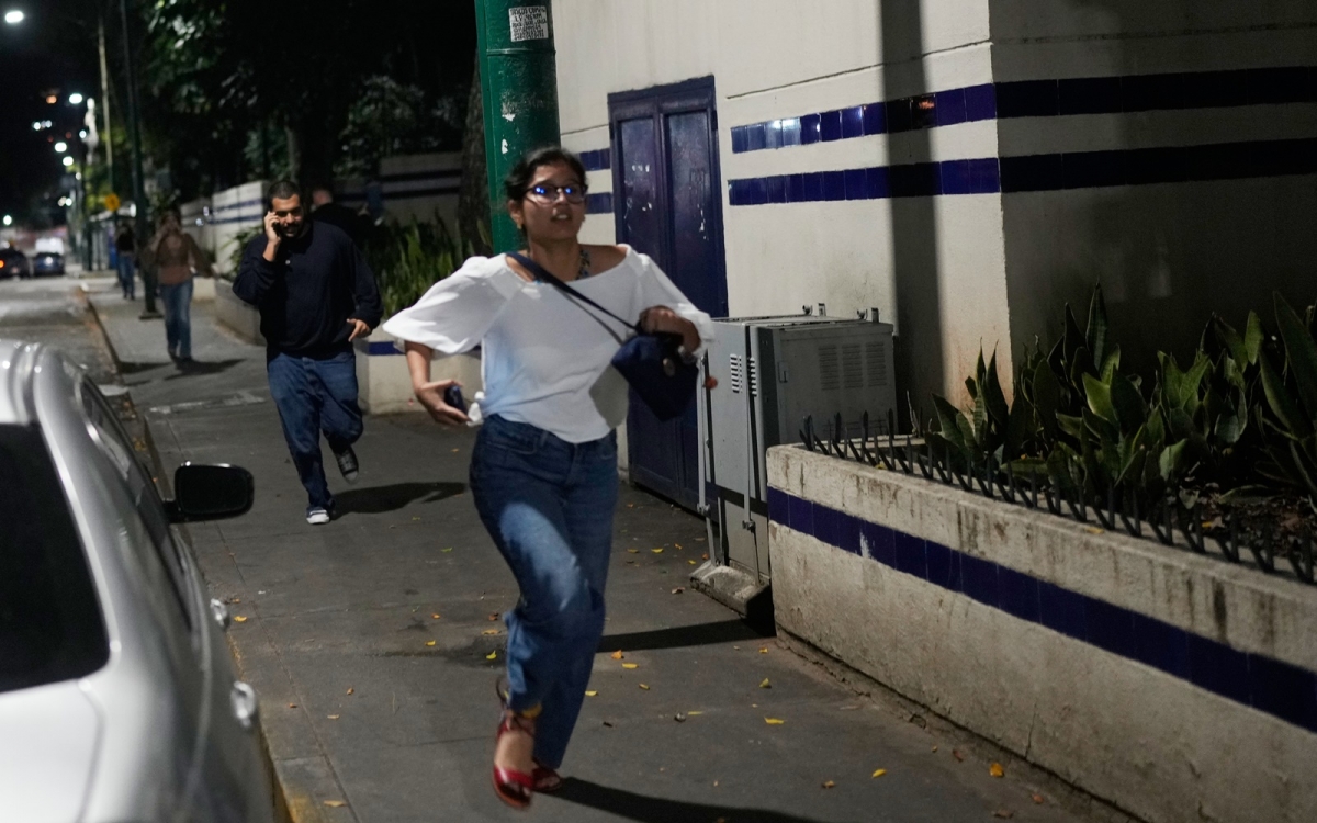 Khách bộ hành chạy vội khi có những tiếng nổ lớn ở Caracas. Ảnh: AP.