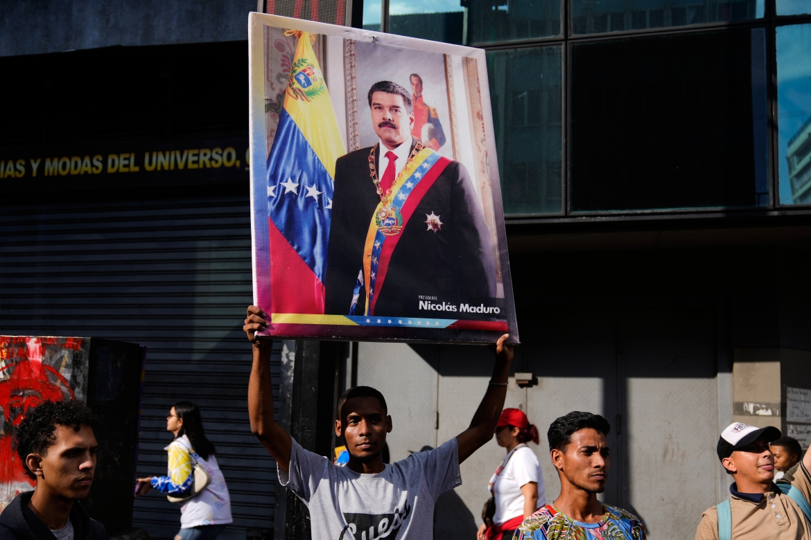 Một người ủng hộ chính phủ giơ banner hình Tổng thống Venezuela Nicolas Maduro trong cuộc biểu tình đòi thả nhà lãnh đạo này sau khi bị Mỹ bắt giữ. Ảnh: AP