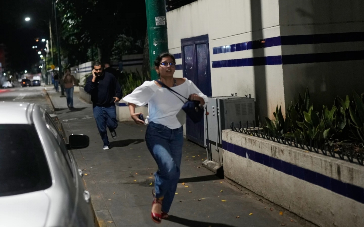 Khách bộ hành chạy vội sau khi có những tiếng nổ lớn ở thủ đô Caracas của Venezuela vào sáng sớm 3/1. Ảnh: AP.