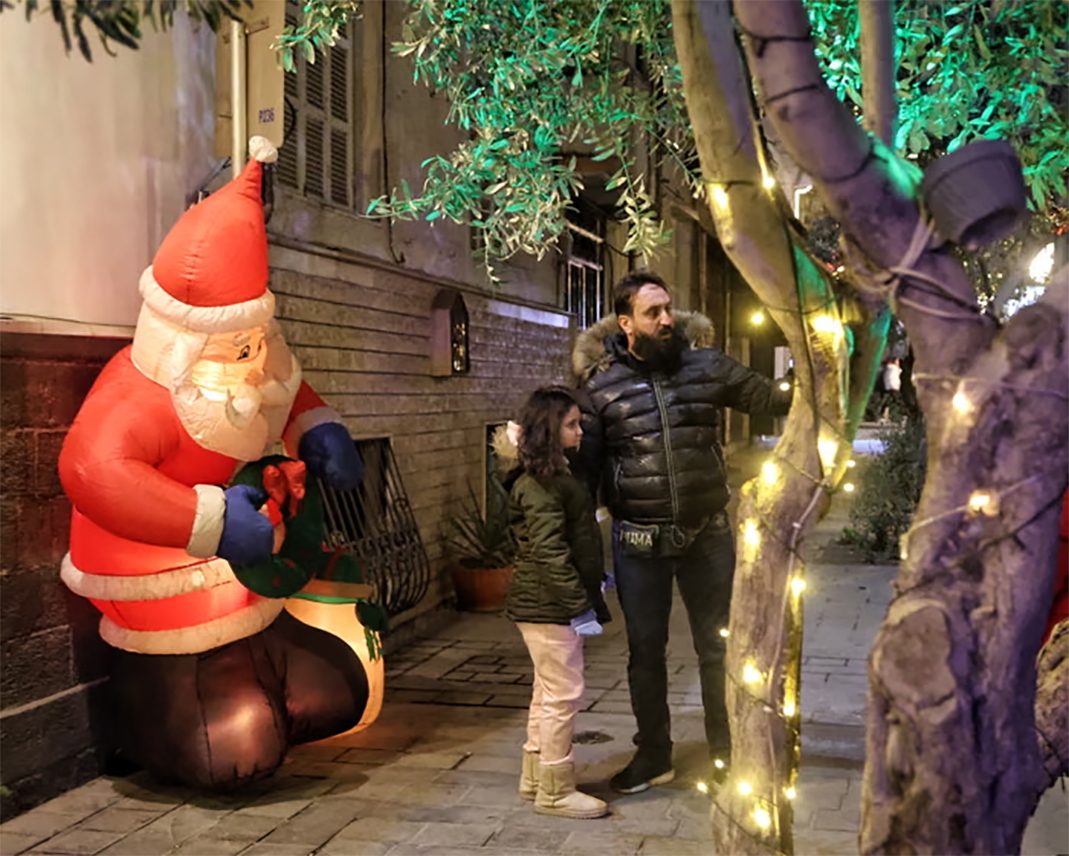 Một người cha và con gái chụp ảnh bên cạnh hình nộm ông già Noel trong lễ đón năm mới ở Damascus, Syria. Ảnh: EPA.