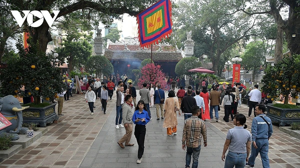 The grounds of Quan Thanh Temple are crowded with local worshippers, blending with international visitors exploring the historic site.