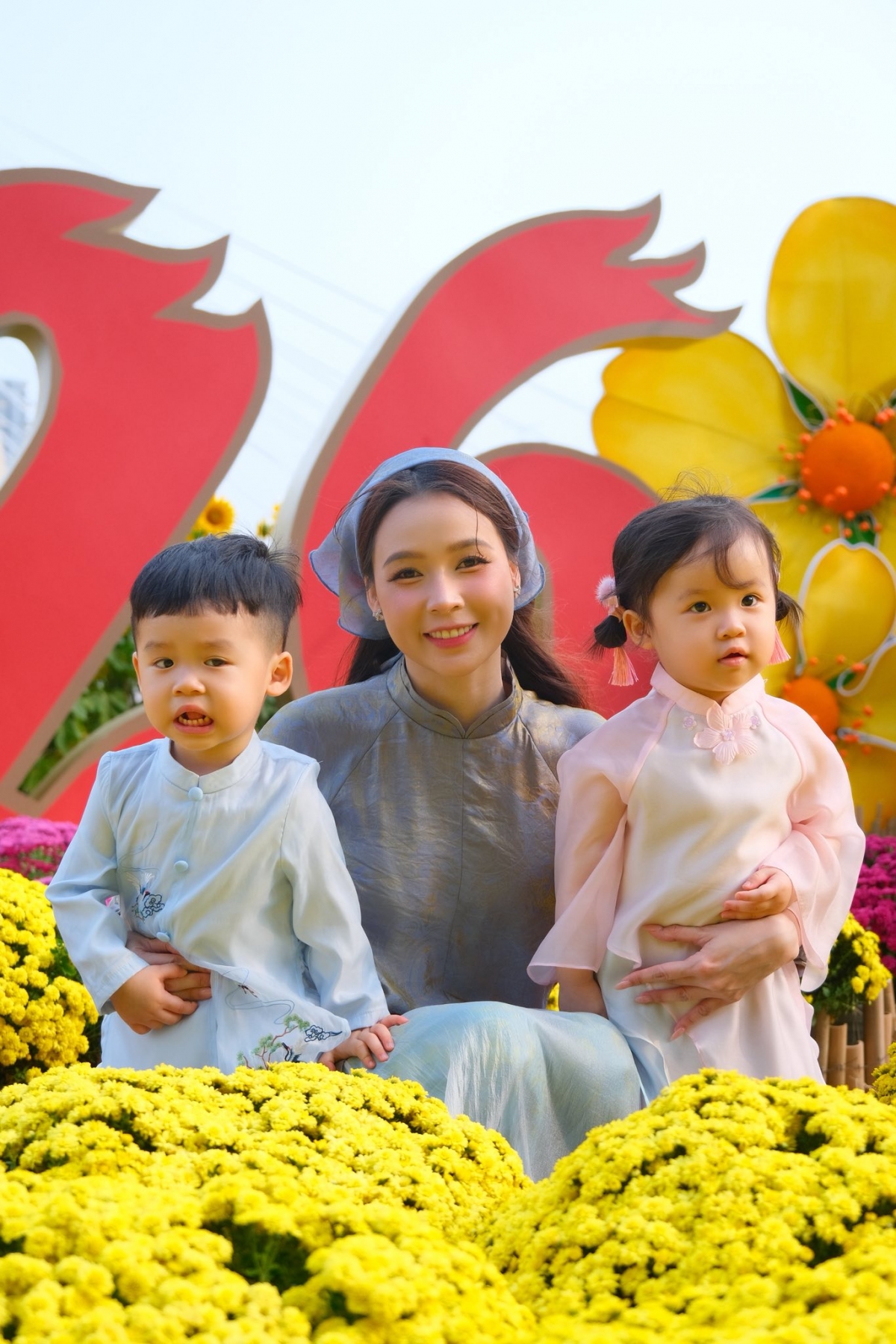 Sam đưa con song sinh đi chợ hoa bên sông Sài Gòn. Ba mẹ con diện áo dài tông màu dịu dàng. Nữ diễn viên cho biết muốn hai con cảm nhận không khí rộn ràng của ngày giáp Tết.