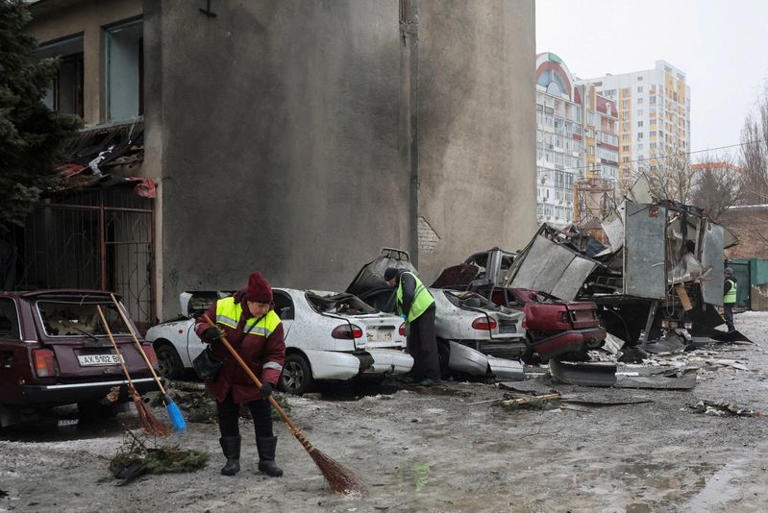 Các nhân viên vệ sinh tại Ukraine quét dọn cạnh đống đổ nát ở Kharkov. Ảnh: Reuters