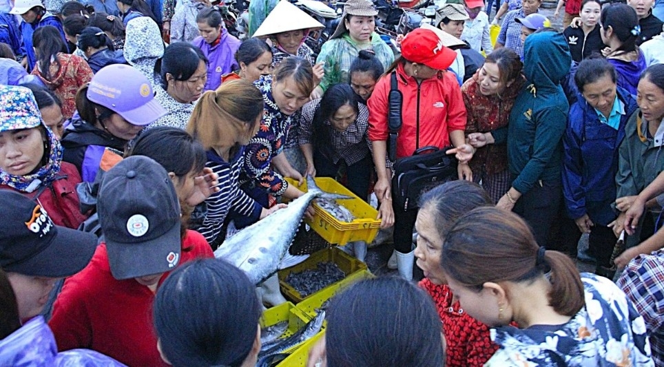 Grilled fish operations peak at dawn as fishing boats return to Nghi Thuy landing site.