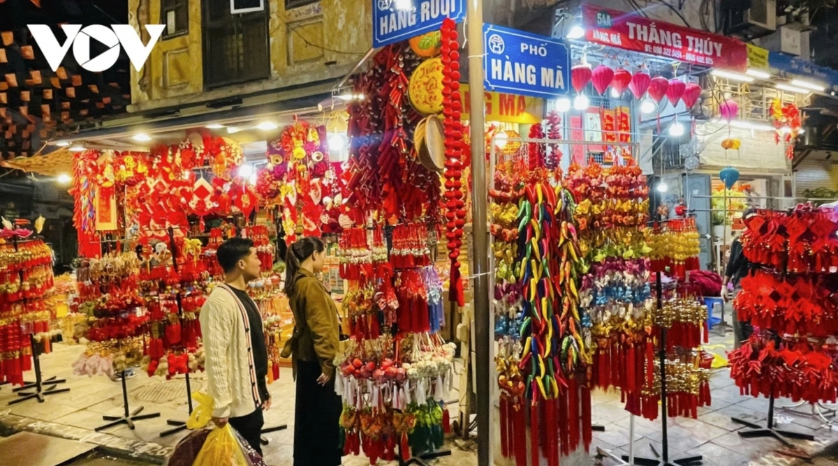 On weekend evenings, stalls along Hang Ma Street are filled with red and gold lanterns, calligraphy scrolls, red envelopes and festive decorations, creating a vivid Lunar New Year scene in Hanoi’s Old Quarter, where streets once known for votive paper trading have become popular photo spots for young people.