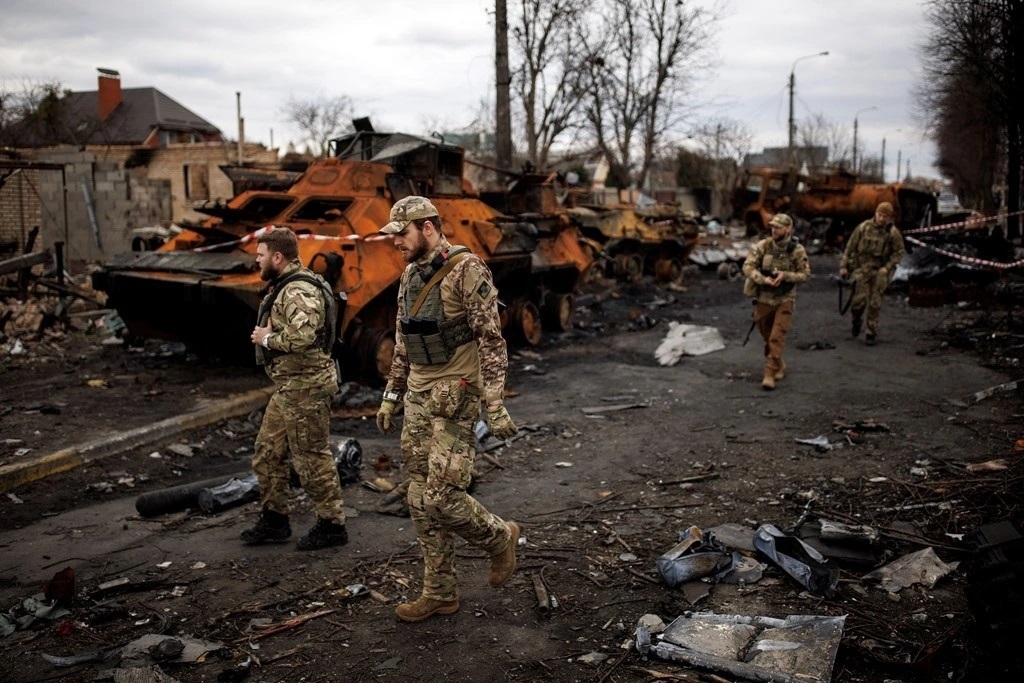 Binh sỹ Ukraine di chuyển cạnh xác xe tăng ở Bucha. (Ảnh: Reuters)