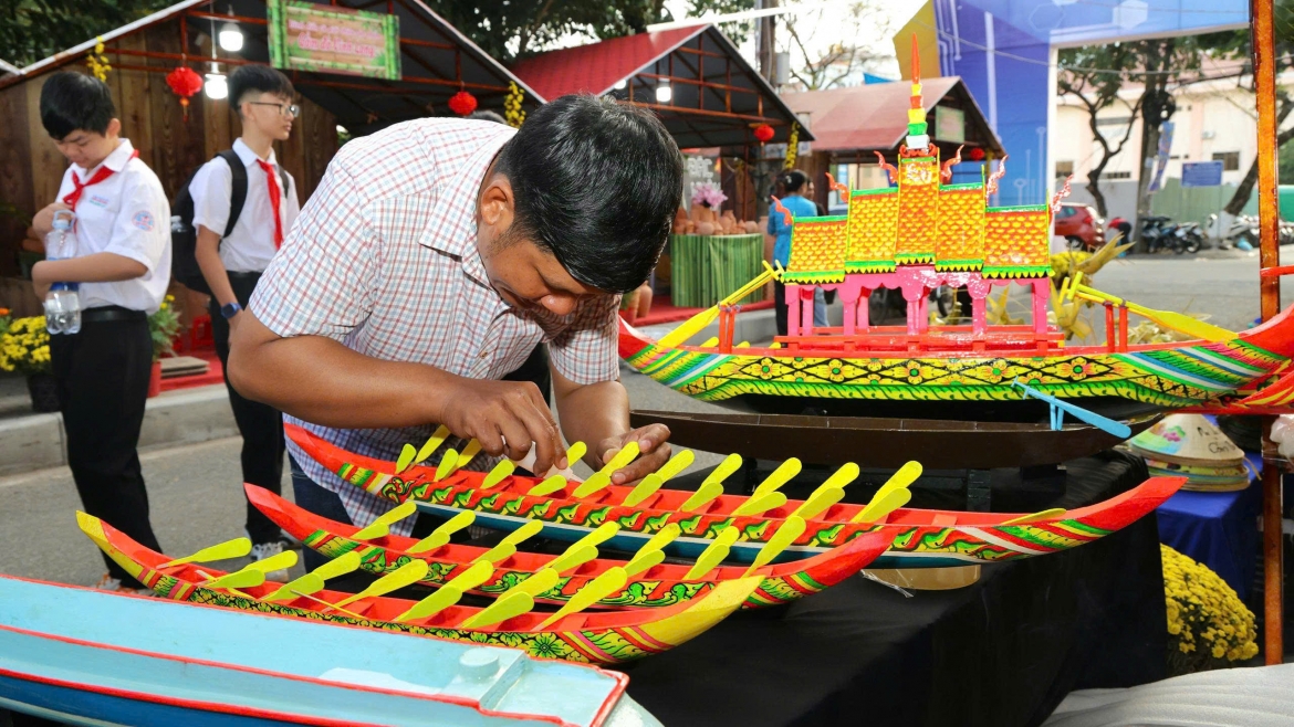 Nghệ nhân trình diễn làm và trang trí ghe ngo - một phương tiện gắn với đồng bào dân tộc Khmer dịp Lễ hội. Từ hình tượng rắn thần Nagar, linh vật của người Khmer làm cá sấu hoảng sợ bỏ chạy để thoát thân, bà con đã sáng tạo ra chiếc ghe mang hình dáng linh vật này