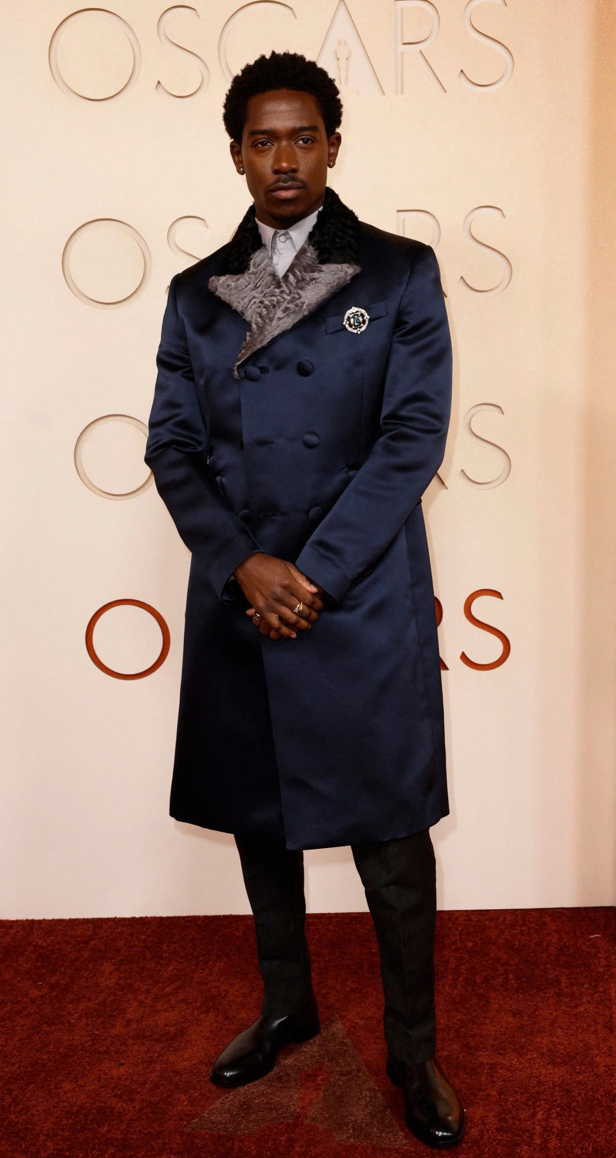 Nam diễn viên Damson Idris diện trang phục của Prada gồm áo khoác satin xanh với ve áo lông, quần tây đen và bốt bóng. Tuy nhiên, tổng thể trang phục bị nhận xét giống trang phục hóa trang hơn là phong cách thảm đỏ trang trọng.