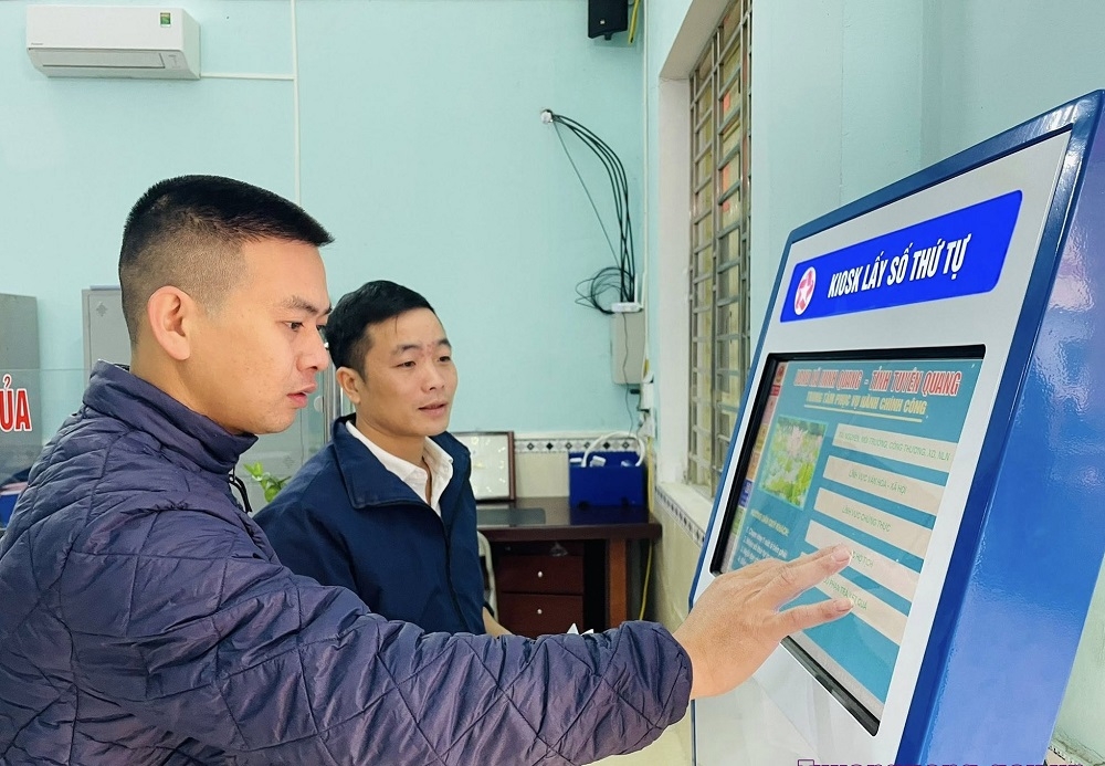 Công chức Trung tâm PVHCC xã Minh Quang hướng dẫn công dân lấy số thứ tự